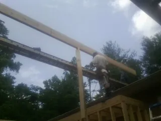 Carpenter setting a ridge beam over a new addition frame — Ice Dam Removal by Roofing Brothers in Okatie