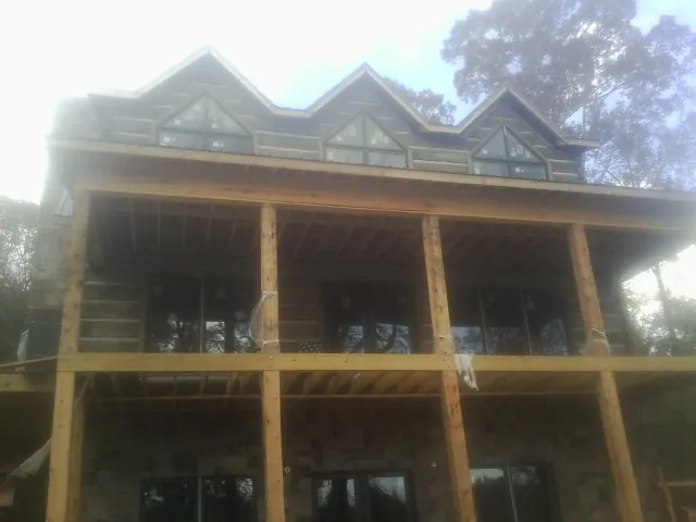 Dormers and porch framing on a large log home under construction — Roof Coating work by our crew in Okatie