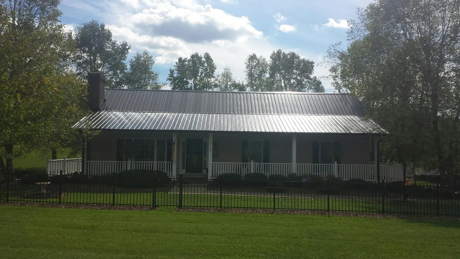 Gray metal roof on a brick ranch with a full width front porch — Gutter Guard Installation work by our crew in Okatie