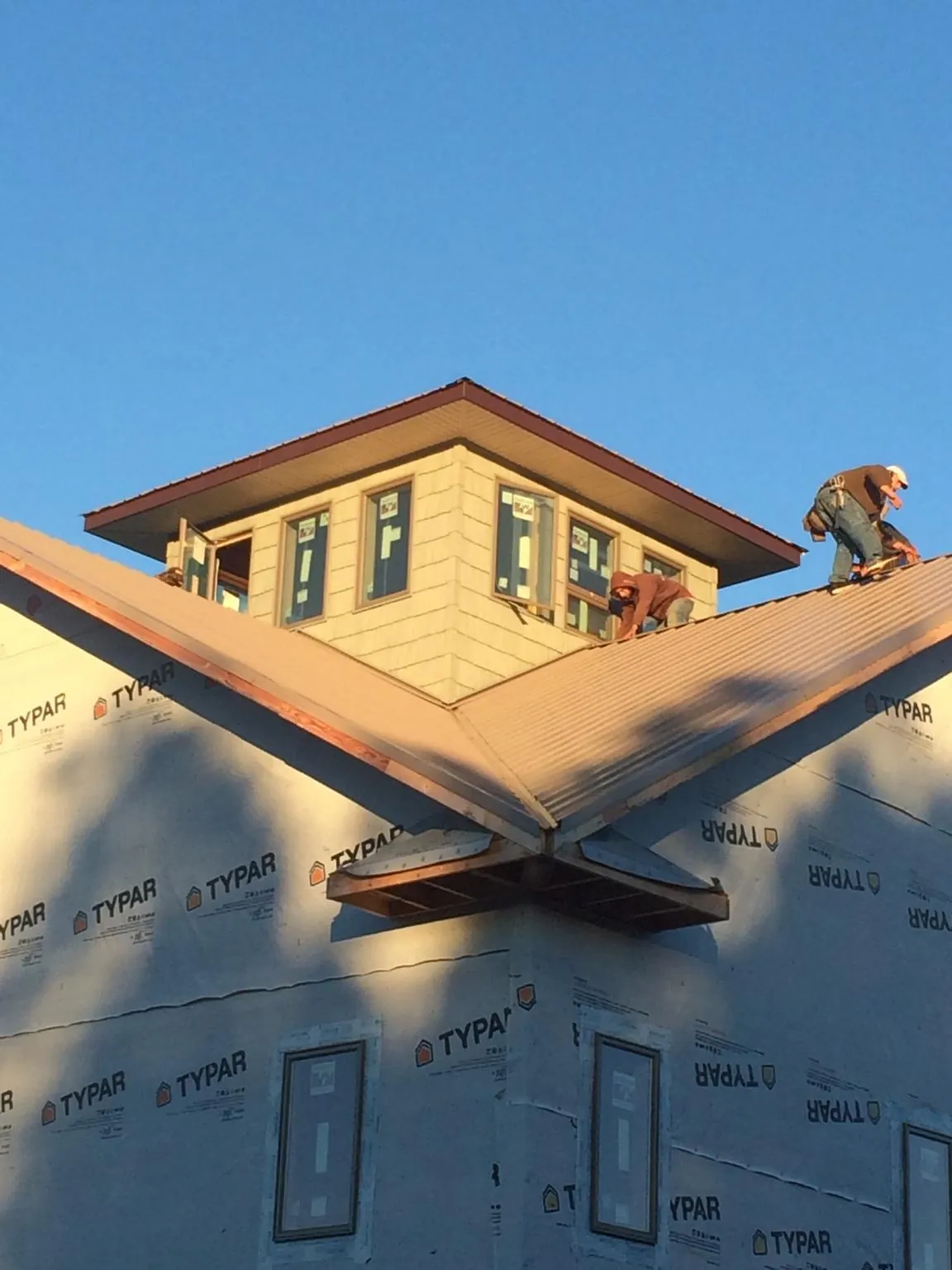 Roofers working around a rooftop cupola on a new metal roof at sunset — Roof Waterproofing in Okatie by Roofing Brothers